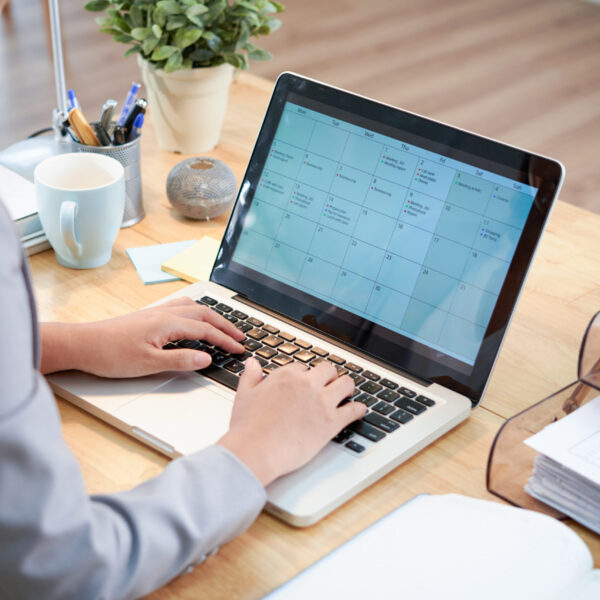 1unrecognizable-businesswoman-sitting-desk-with-laptop-looking-calendar